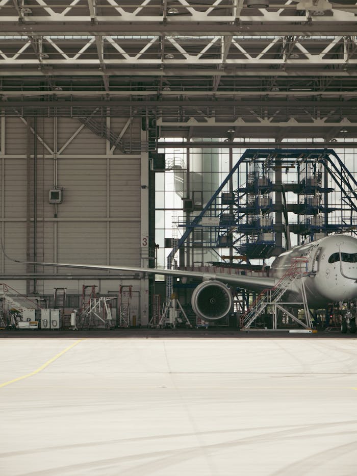 Services Detailed view of a commercial airplane undergoing maintenance inside an industrial hangar.